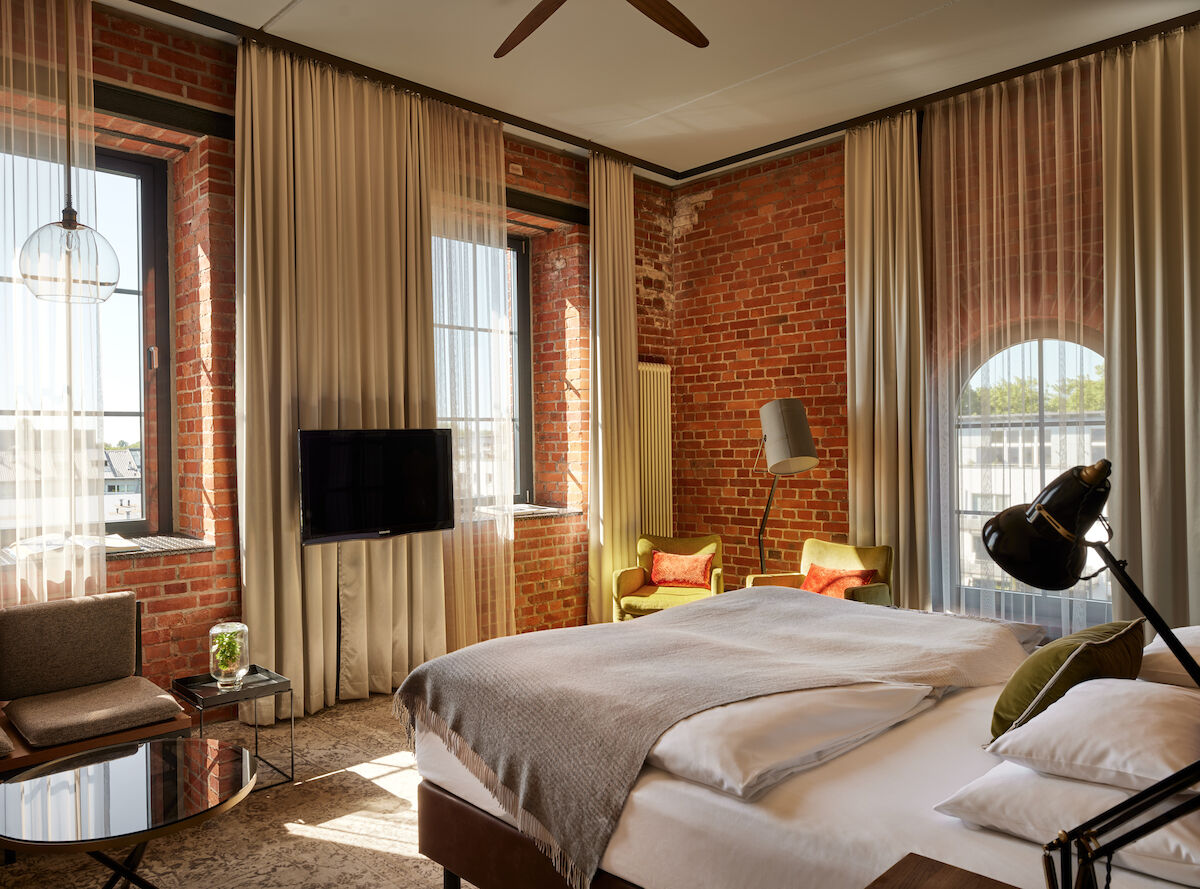 Gastwerk Hotel Hamburg Zimmer L Loft 552 02 L Loft des Gastwerk Hotel Hamburg mit Bett, Backsteinwand und gelben Sesseln