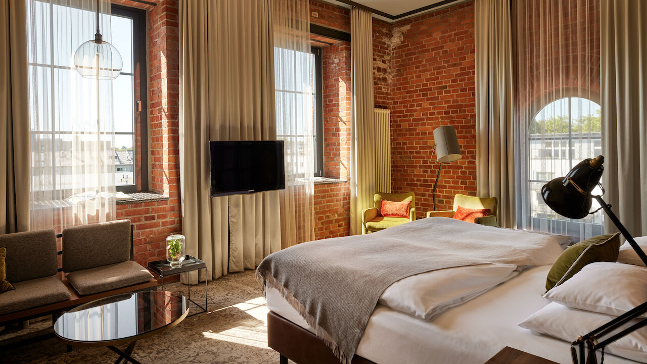 Gastwerk Hotel Hamburg Zimmer L Loft 552 02 L Loft des Gastwerk Hotel Hamburg mit Bett, Backsteinwand und gelben Sesseln