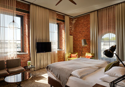 Gastwerk Hotel Hamburg Zimmer L Loft 552 02 L Loft des Gastwerk Hotel Hamburg mit Bett, Backsteinwand und gelben Sesseln