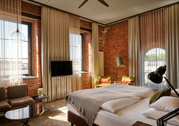 Gastwerk Hotel Hamburg Zimmer L Loft 552 02 L Loft des Gastwerk Hotel Hamburg mit Bett, Backsteinwand und gelben Sesseln