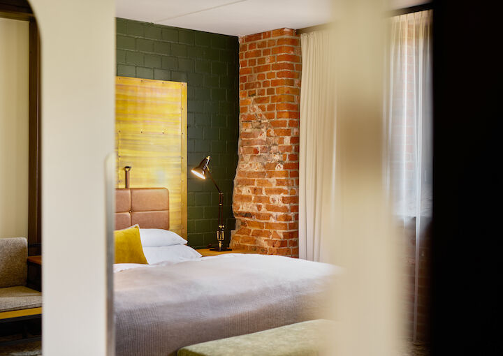 Gastwerk Hotel Hamburg Zimmer L Loft 124 01 L Loft mit großem Bett im Anschnitt und Backsteinwand im Hintergrund