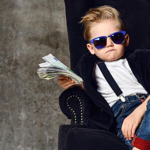 Cooles Kind mit Sonnebrille hält ein Bündel Geldscheine in der Hand